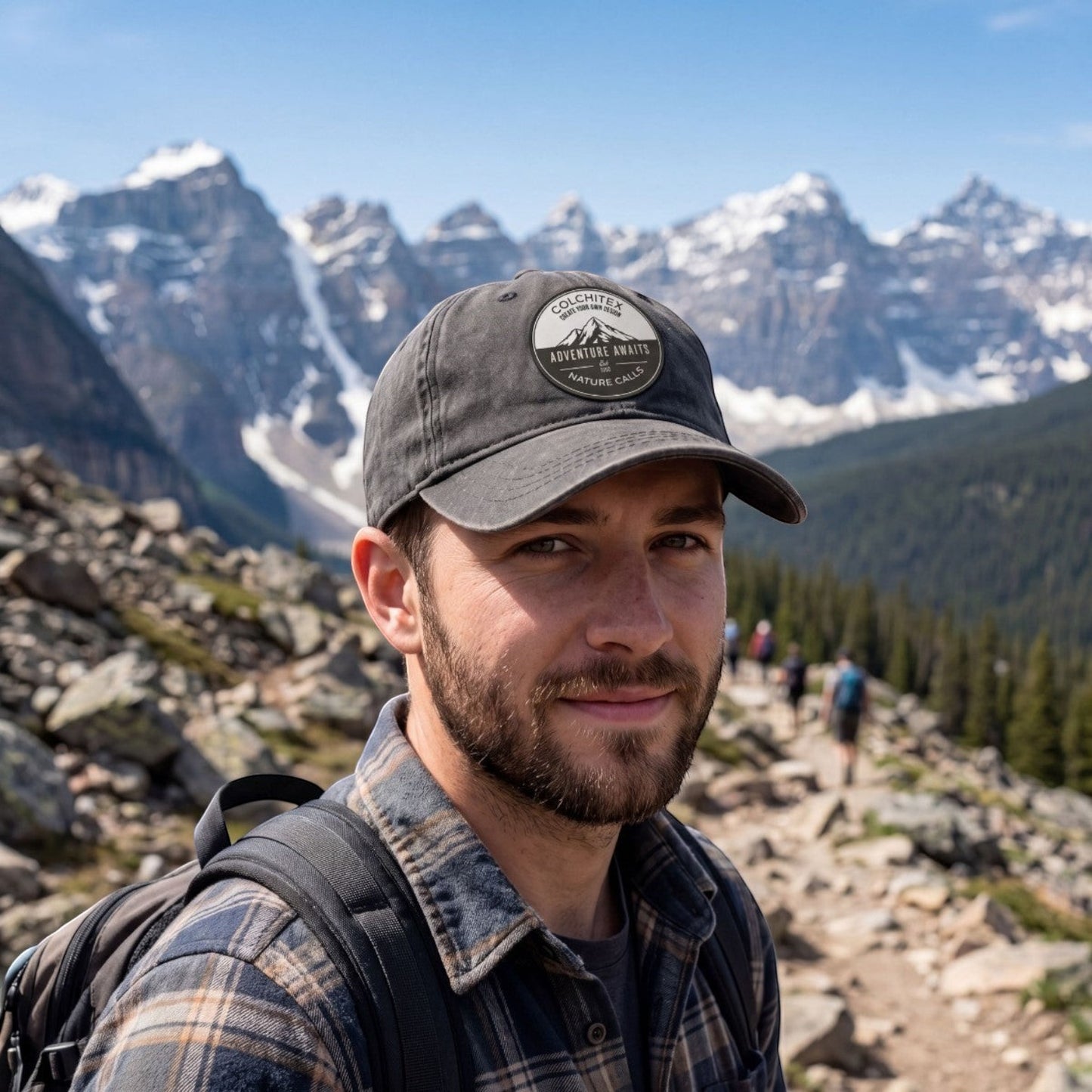 ColChiTex LLC dark grey trucker hat with custom engraved patch featuring mountains and text "Adventure Awaits Nature Calls