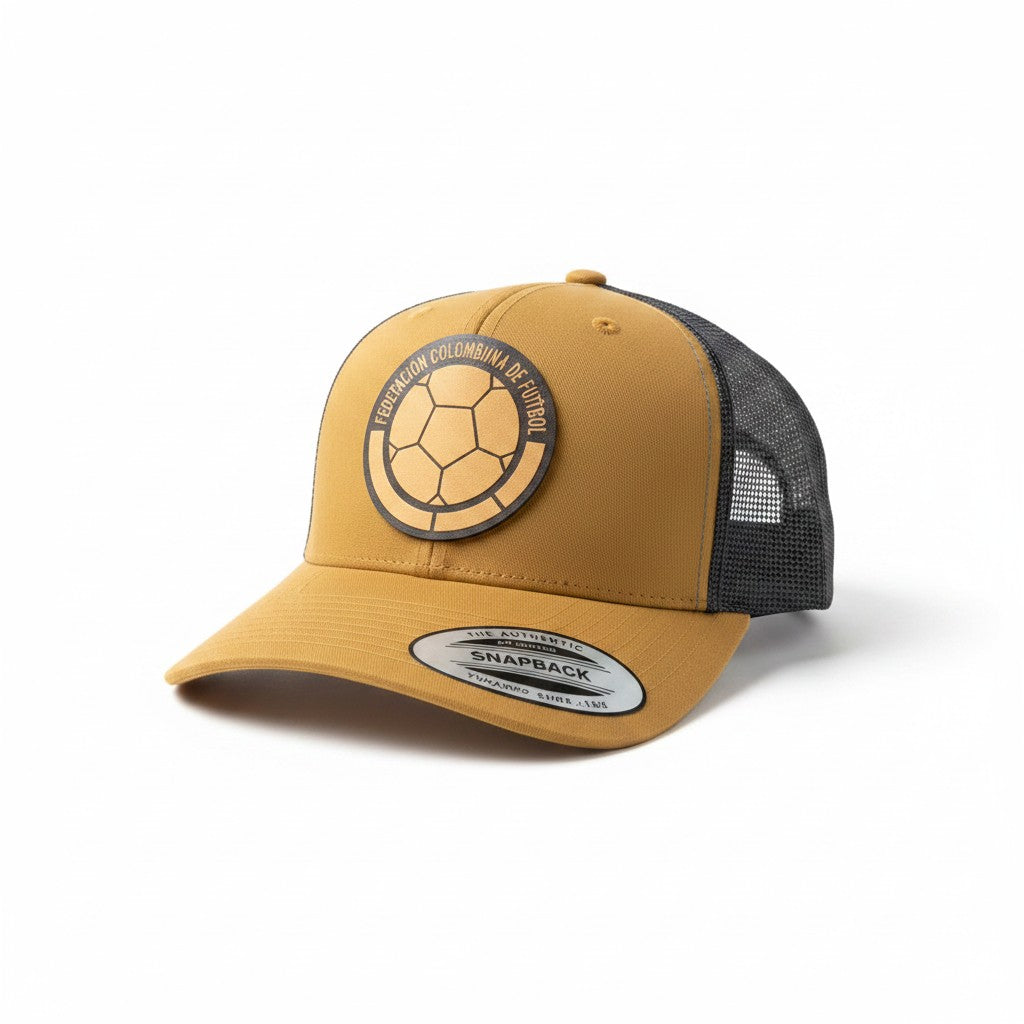 ColChiTex LLc custom engraved patch trucker hat in mustard yellow with a dark grey mesh back and a circular patch featuring a soccer ball and text.